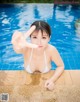 A woman in a white bikini posing by a swimming pool.