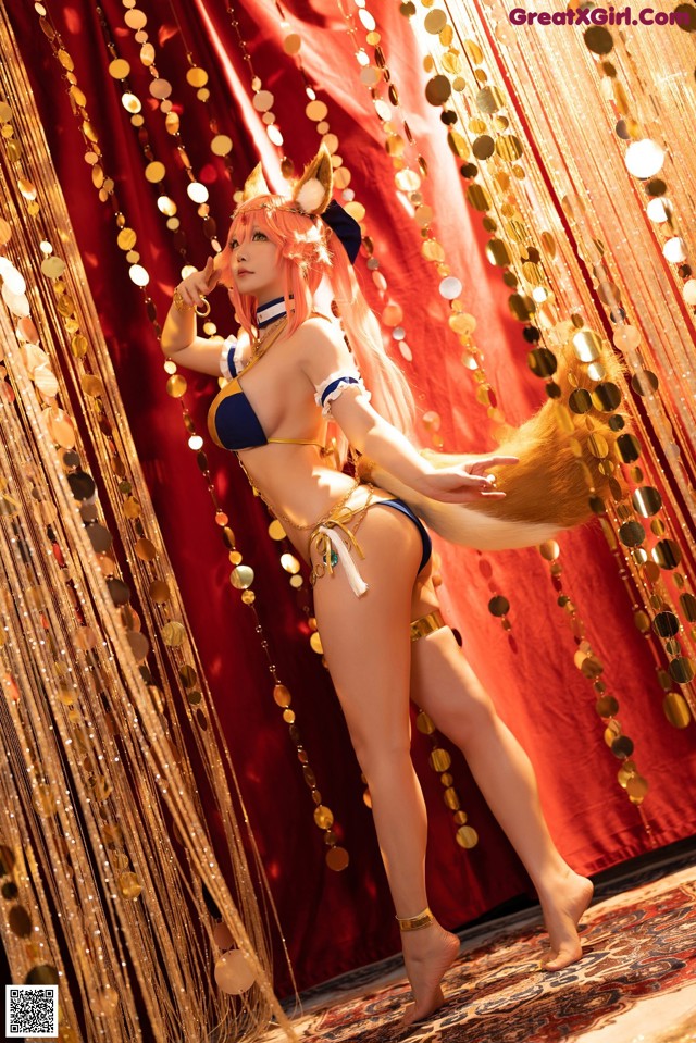 A woman in a bikini standing in front of a curtain.