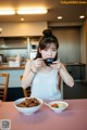 A woman sitting at a table eating a bowl of food.