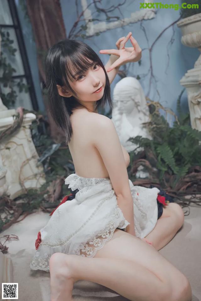 A woman in a white dress sitting on the ground.