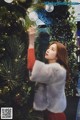 A woman in a fur coat decorating a Christmas tree.