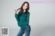 a woman in a green sweater and jeans posing for a picture