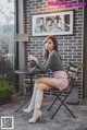 A woman sitting on a chair in front of a brick wall.