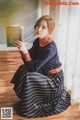 A woman sitting on the floor holding a book.