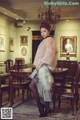 A woman in a pink fur coat standing in a dining room.