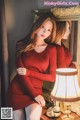 A woman in a red dress sitting in front of a mirror.