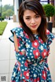 A woman in a blue dress with red and white flowers.