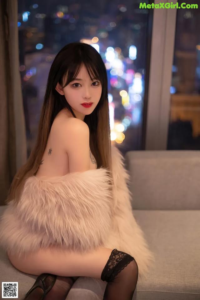 A woman sitting on a couch in a fur coat.