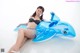 A woman in a bikini sitting on an inflatable whale.