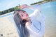 A woman with long gray hair standing on a beach.