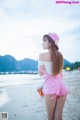 A woman standing on a beach holding a cup of coffee.