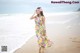 A woman in a colorful dress walking on the beach.