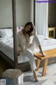 A woman sitting on a bed in a bedroom.