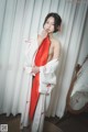 A woman in a white and red kimono posing for a picture.