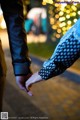 A man and a woman holding hands in front of a tree.