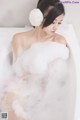 A woman sitting in a bathtub covered in foam.