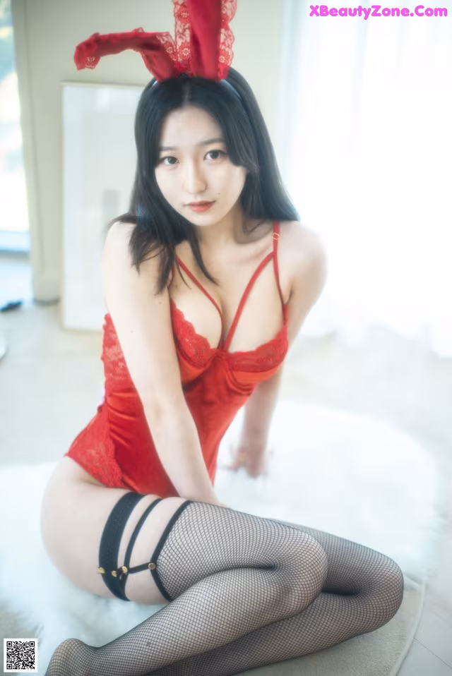 A woman in a red lingerie sitting on a white rug.