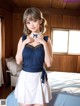 A woman in a blue top and white skirt standing on a bed.