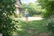 A woman walking down a path in the middle of a lush green field.