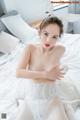 A woman in a white corset sitting on a bed.