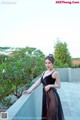 A woman in a black dress standing on a balcony.