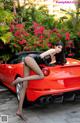 A woman sitting on top of a red sports car.