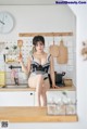 A woman sitting on top of a kitchen counter holding a spatula.