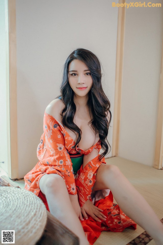 A woman in a red kimono sitting on the floor.
