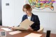 A woman sitting at a table writing on a piece of paper.