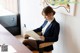 A woman sitting at a desk reading a piece of paper.