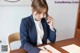 A woman sitting at a desk talking on a cell phone.